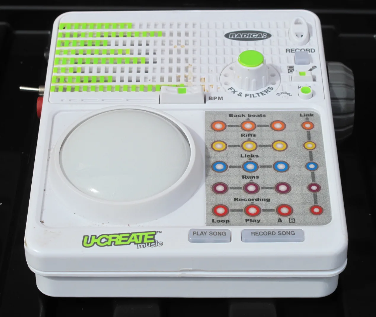 The UCreate Music seen from a low front angle, showing the large light-up control button on the front panel.