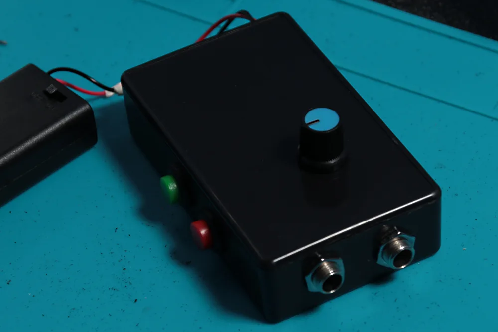 The finished lo-fi sampler in its enclosure, with 1/4-inch input and output jacks, red record and green playback buttons, a pitch knob, and an external battery pack.