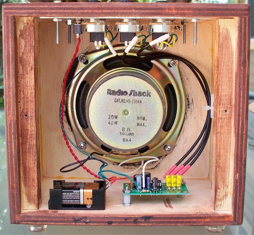 The amplifier with its back open, showing the speaker, battery holder and PC board inside the plywood box.