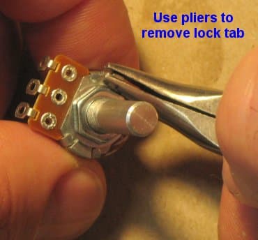 Pliers gripping the break-off tab low on a smaller-sized pot, ready to twist it off.