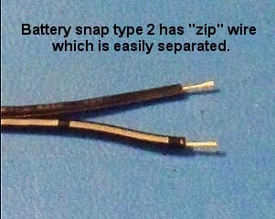 A type 2 battery snap with its two black zip wires pulled apart near the stripped end.