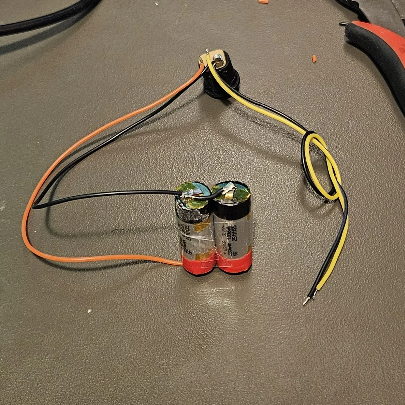 The finished pack: two cells taped together, wired to the switched DC jack, leads tidy on the mat.