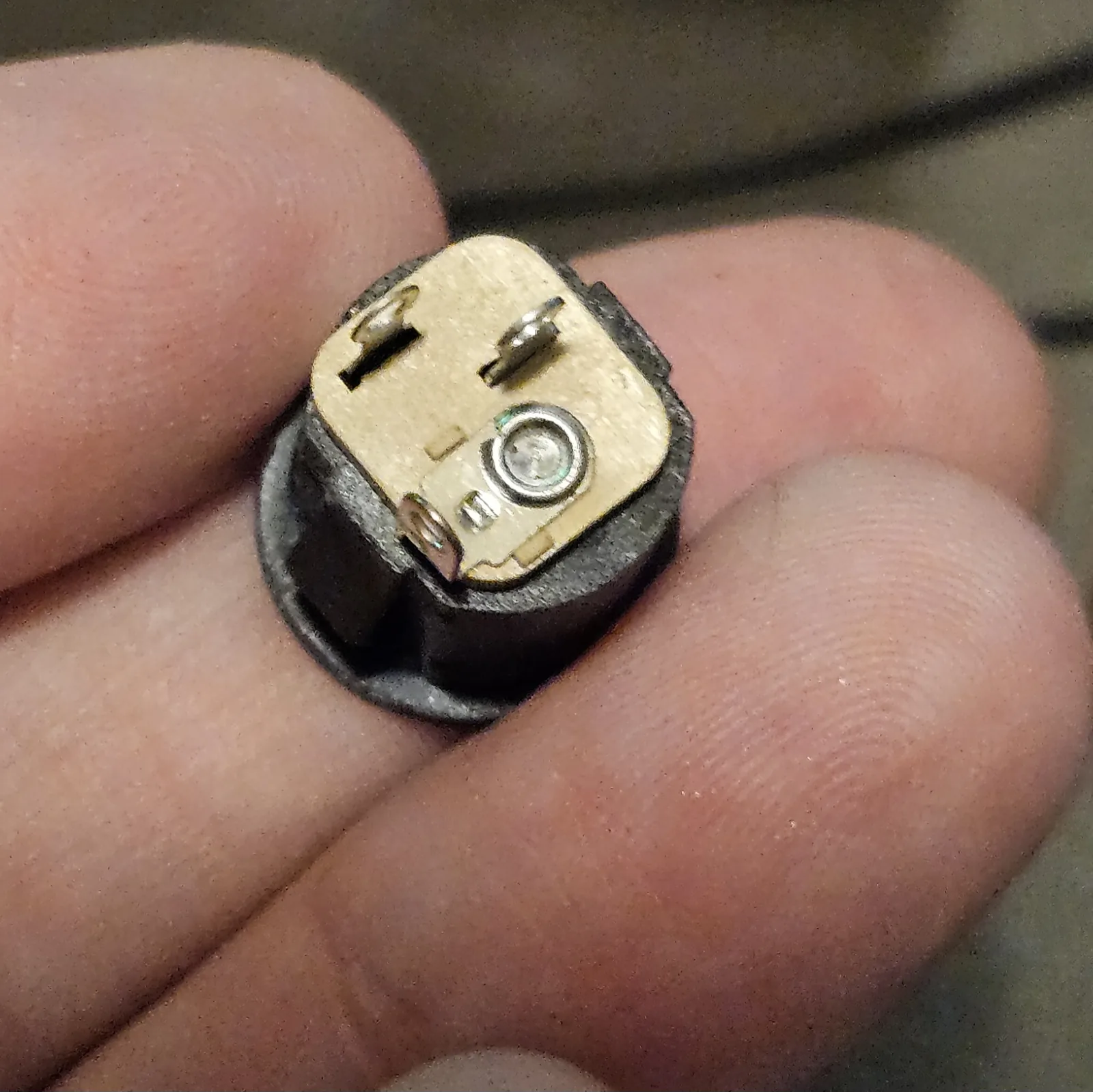 A close-up of the black switched barrel DC power jack held in the fingers.