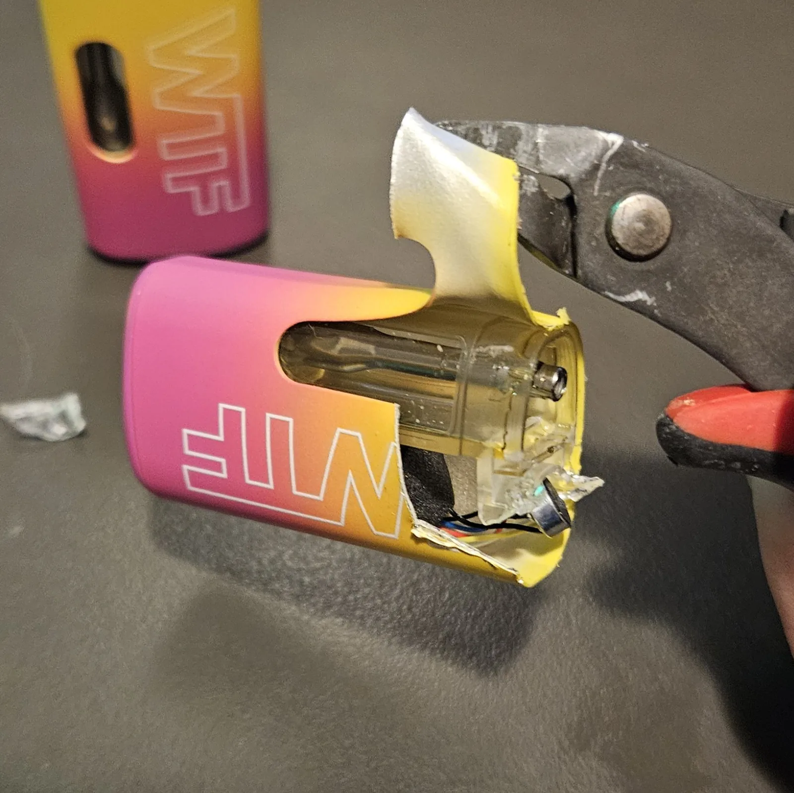 Pliers peeling the clear plastic wrap off the lithium cell, the bare cell showing through.