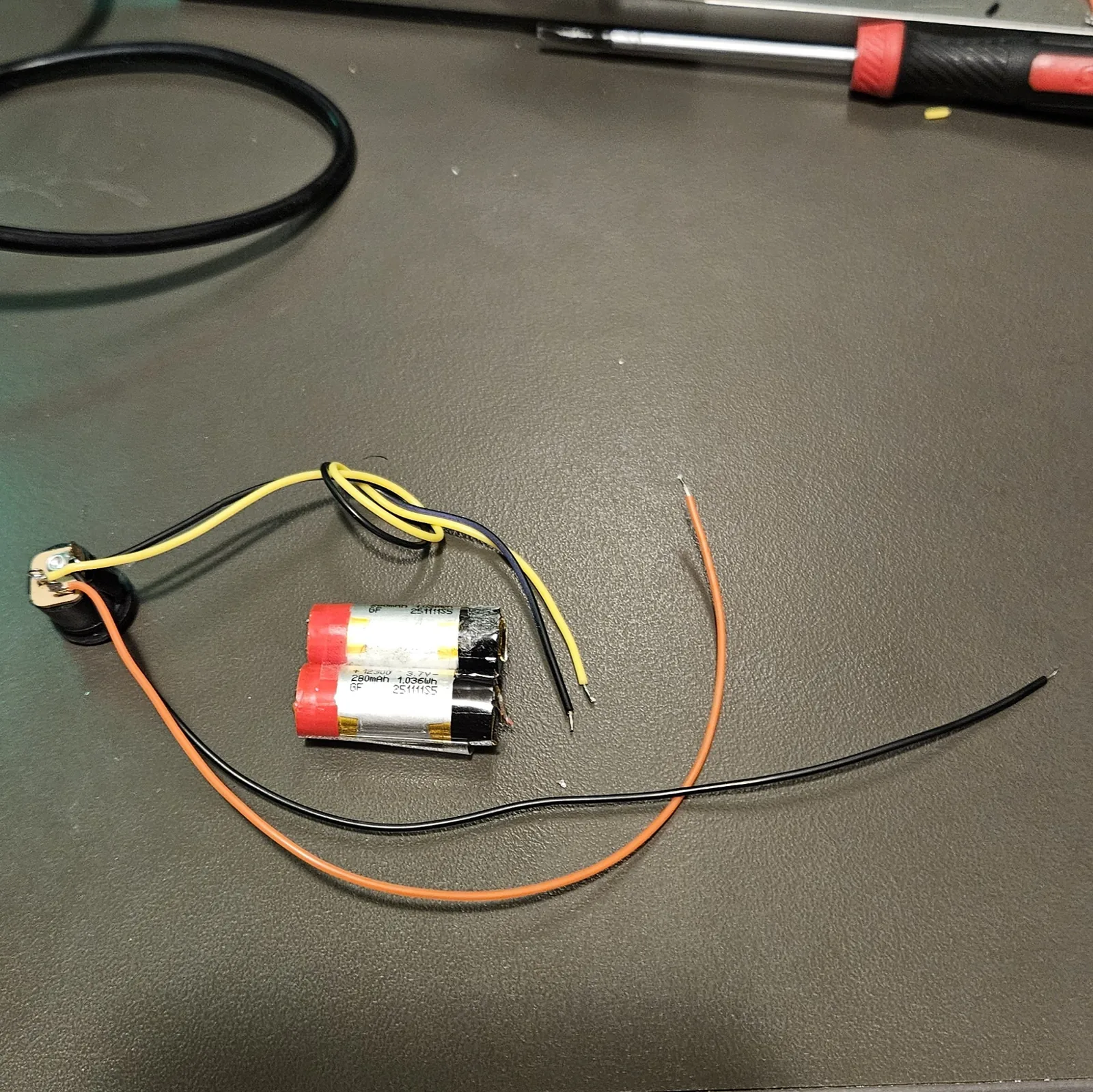 The two salvaged cells taped together beside the wired DC jack and loose wires, ready to join up.