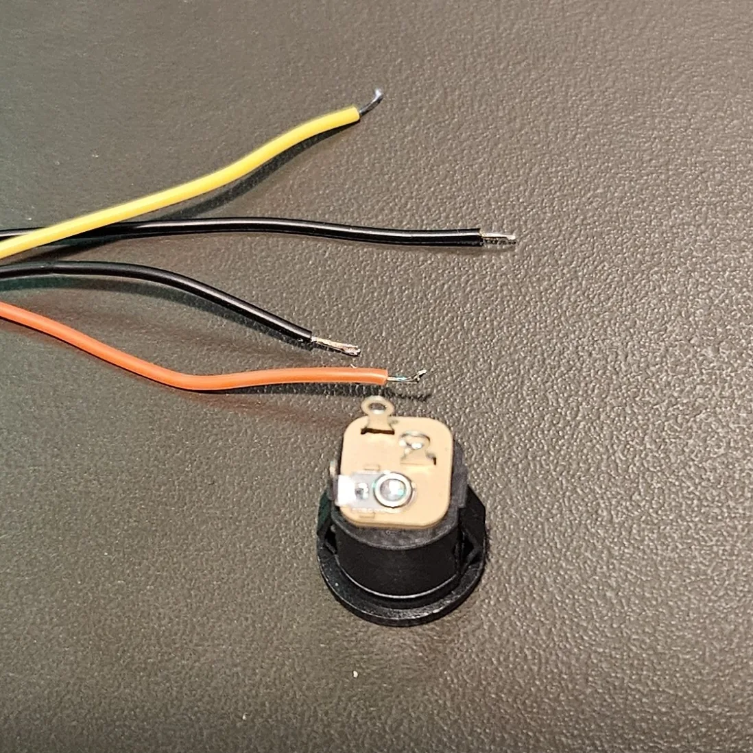 The round switched DC power jack with yellow, orange, and black wires laid out, tinned and ready to solder.