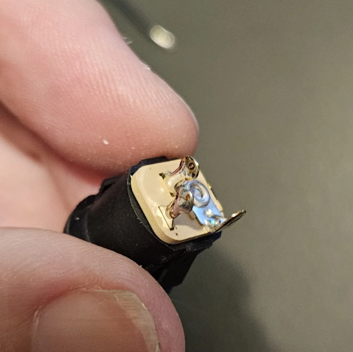 A hand holding the DC jack, showing a clean, shiny solder joint on its lug.