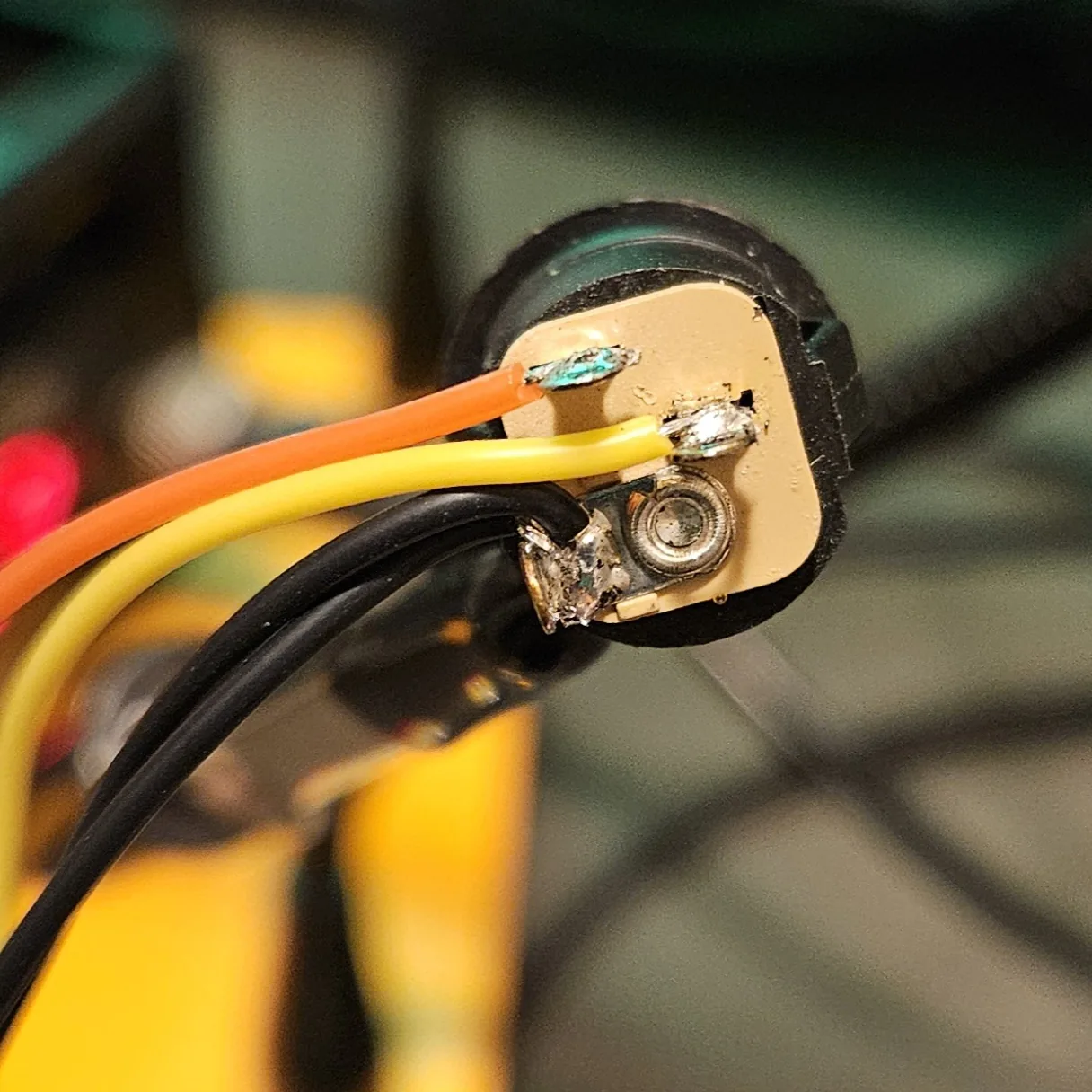 The DC jack fully wired, with orange, yellow, and black wires soldered to its lugs.