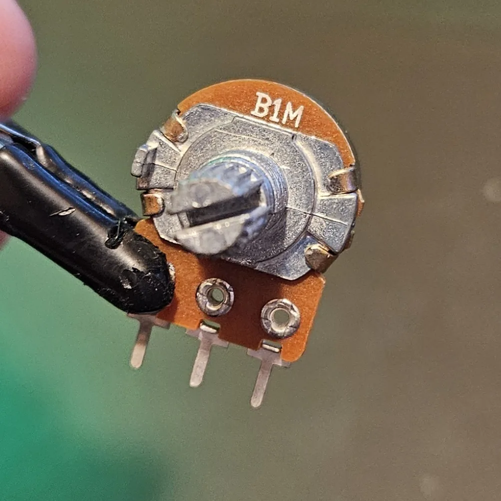 A single potentiometer standing on the bench, splined shaft, threaded bushing and three solder lugs.
