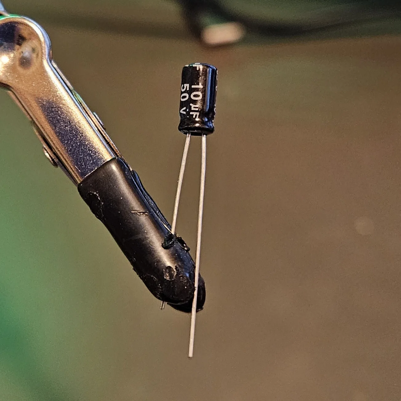 A small cylindrical electrolytic capacitor with a stripe down one side marking its negative leg.