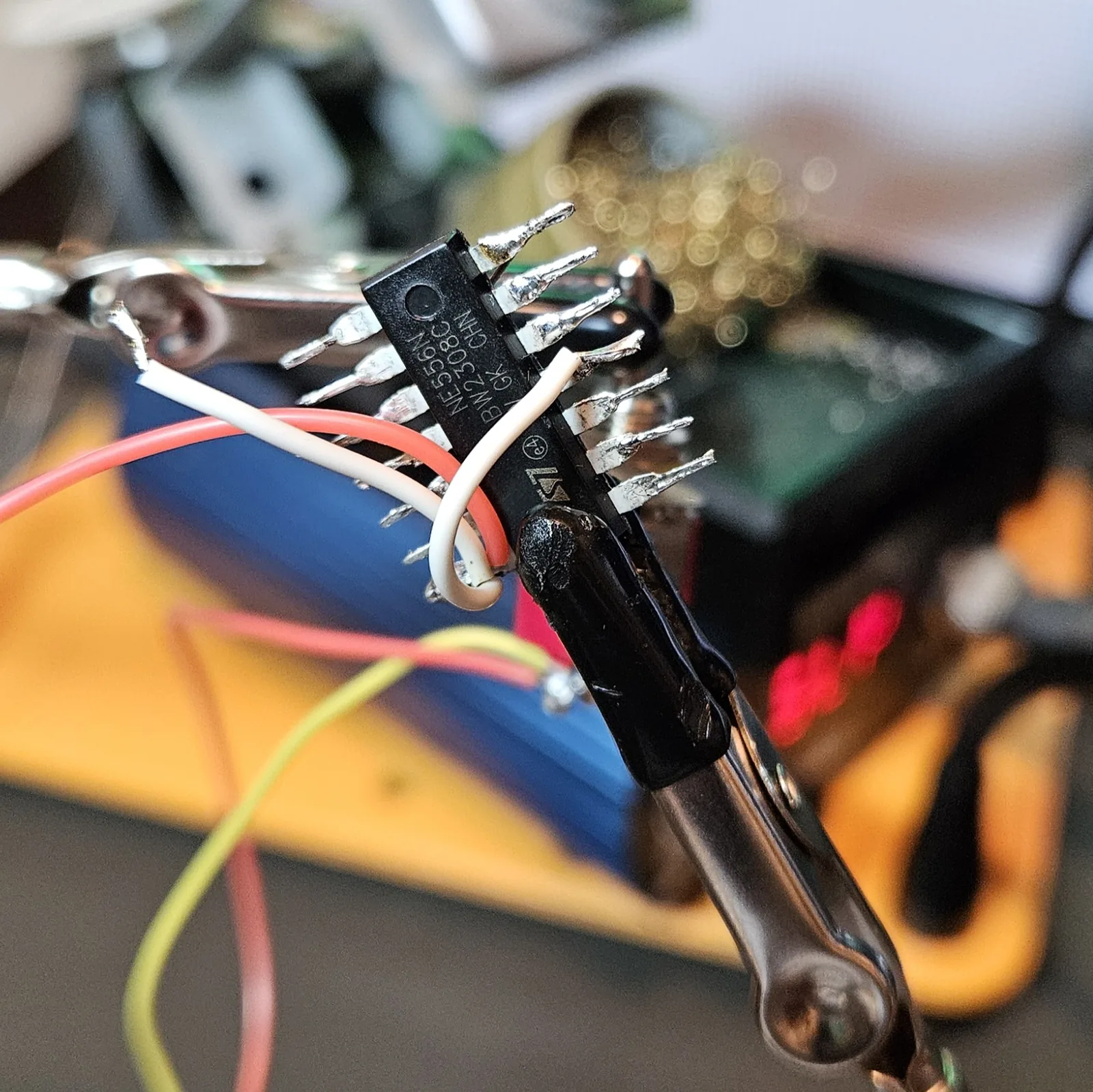 The reset jumpers soldered down, white wires looping from the reset pins over to the V-plus rail, with red and black supply wires hanging below the chip.