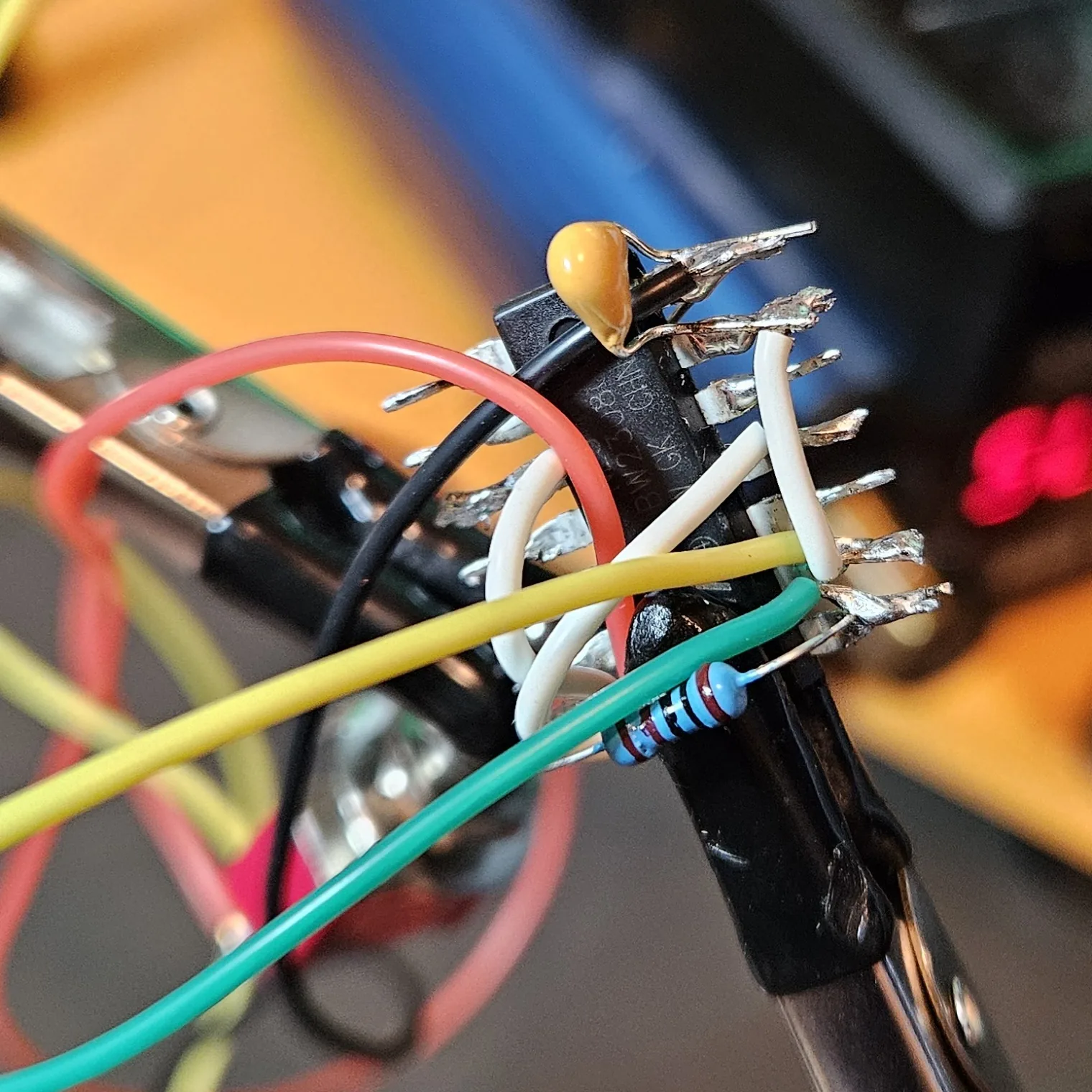 The yellow 0.01 microfarad timing cap soldered onto the chip, tying the tied-together threshold and trigger pins down to ground.