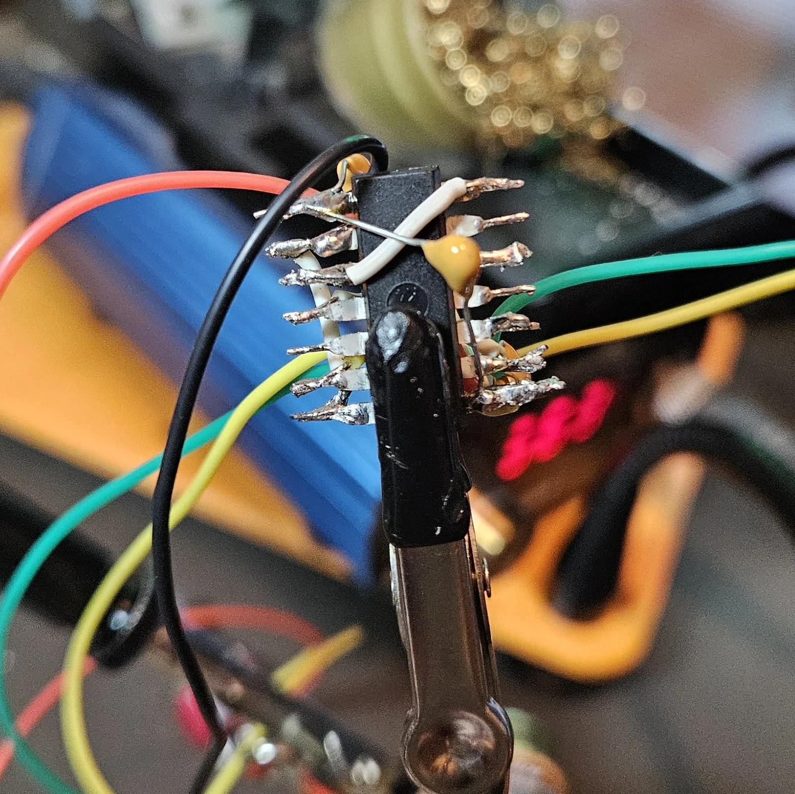 Both timers wired: two yellow timing caps, white jumpers, red and black power leads, and the green and yellow pot leads all soldered onto the dead-bug NE556 in the clamp.