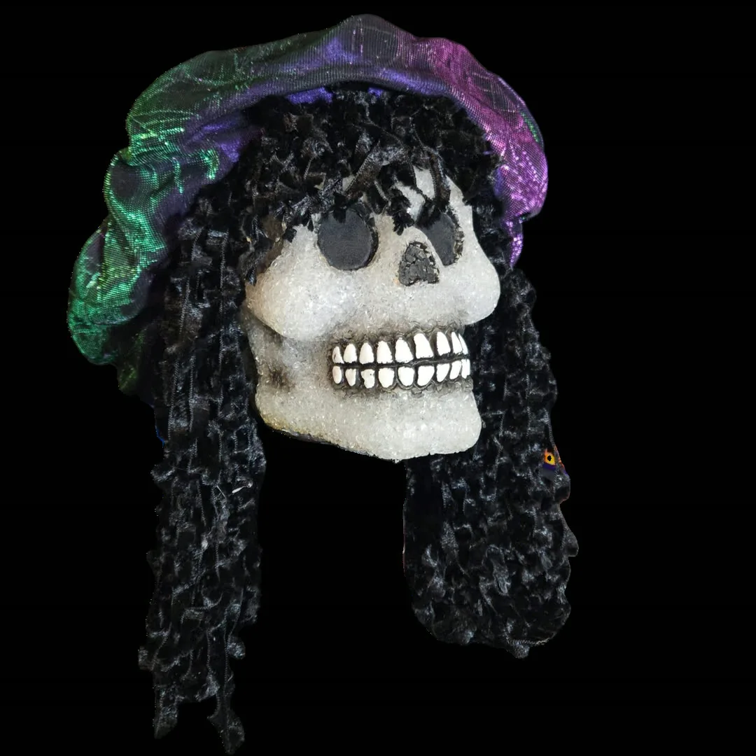 Bent Brooks - a decorated skull with a crystalline white finish, long black ringlet curls, and an iridescent purple-and-green cap, housing a lo-fi ISD1820 sampler module