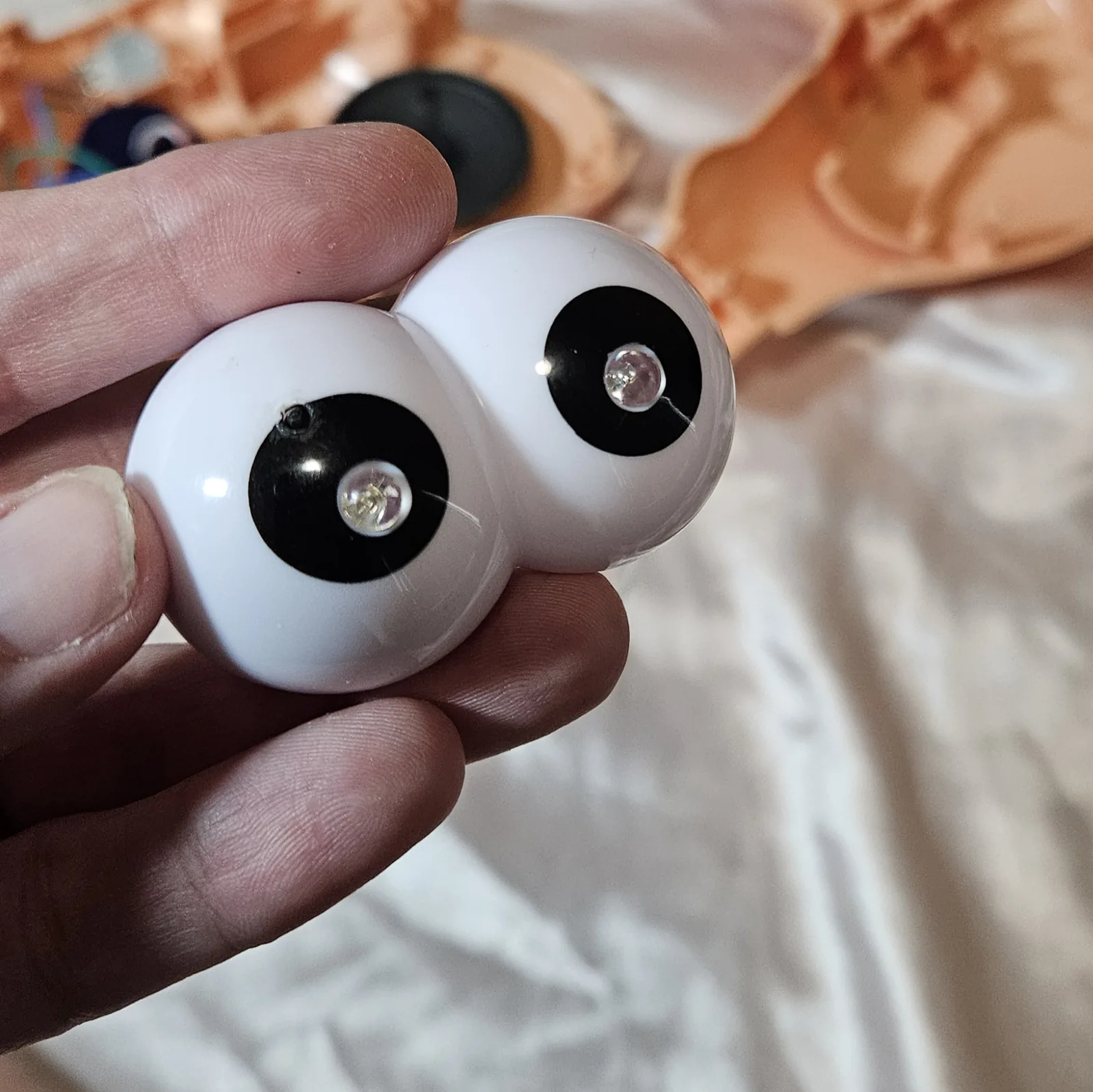 Close-up of the two eyeballs in hand, clear LED domes seated in the black pupils - one eye has an extra small hole drilled just off-center.