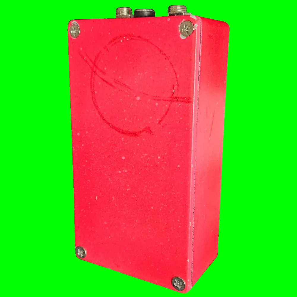 Back of the pedal: a plain red bottom plate with a Phillips screw in each corner and a faint circular scuff worn into the paint near the top. The two jacks and the DC socket show along the top edge.