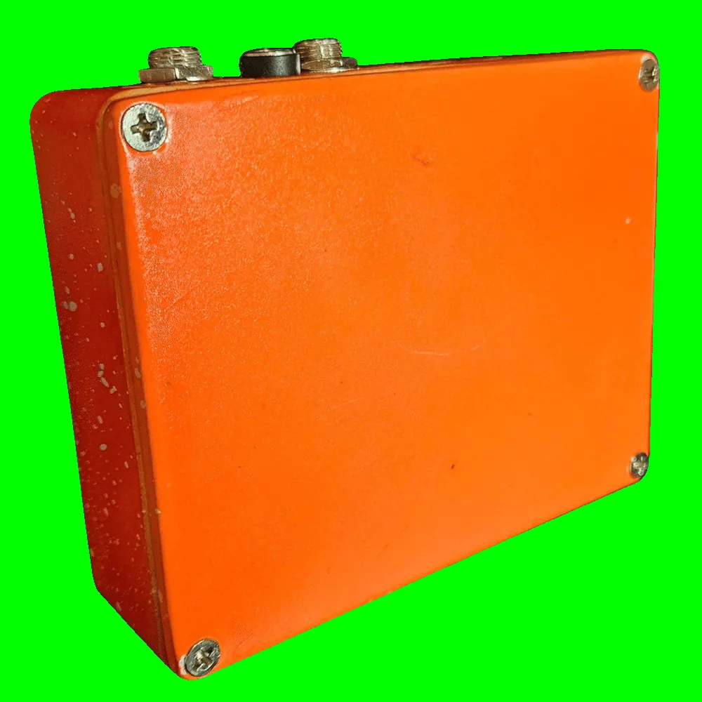 Back of the pedal: a plain glossy orange bottom plate with a Phillips screw in each corner and no label or artwork. The two jacks and the DC socket line the top edge.