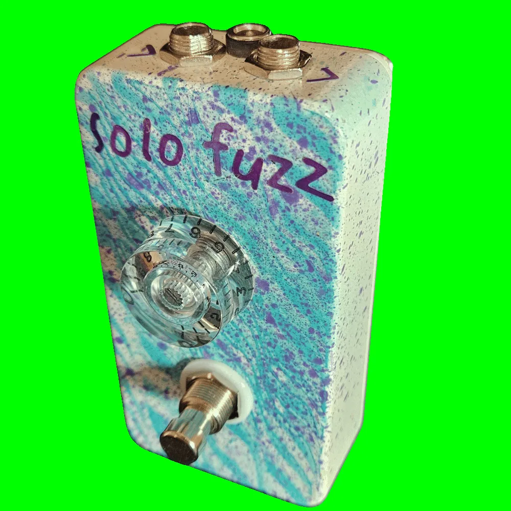 Top-down view of the enclosure: a 1/4-inch jack sits at each corner of the top edge with a black DC power jack between them, and the jacks carry no legible labels. Hand-lettered purple "solo fuzz" sits above the single clear knob.
