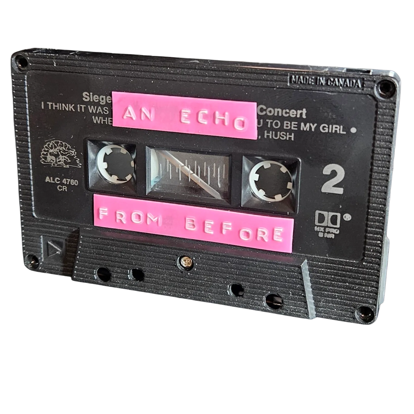 Black cassette shell with two pink hand-lettered labels reading An Echo and From Before, recycled from an old concert cassette