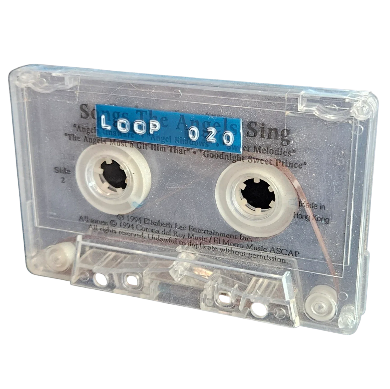 Clear cassette shell labeled Loop 020 on a blue strip, recycled from a 1994 Songs The Angels Sing cassette