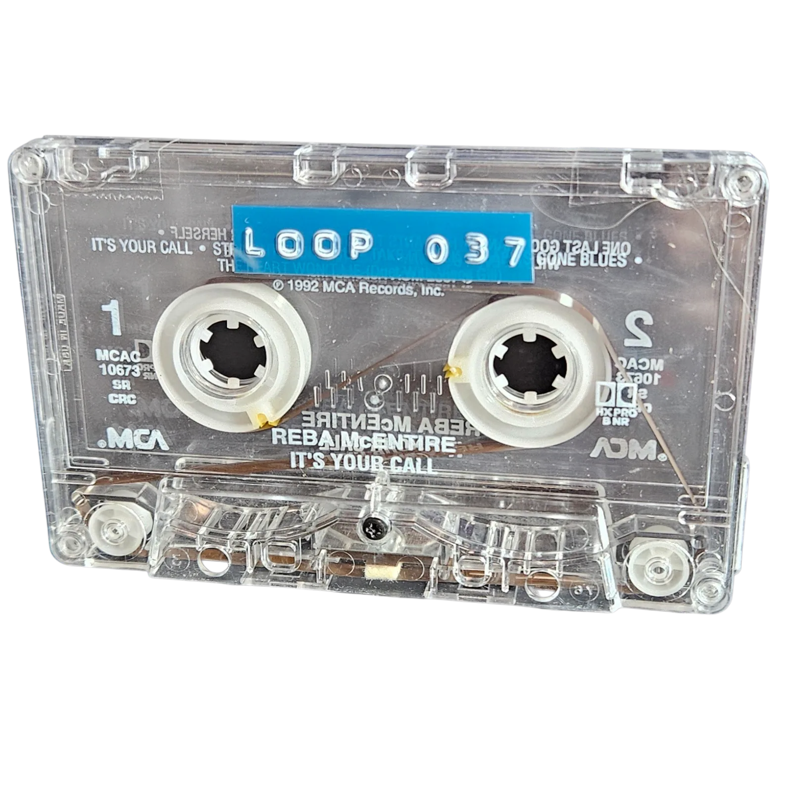 Clear cassette shell labeled Loop 037 on a blue strip, recycled from Reba McEntire's It's Your Call cassette