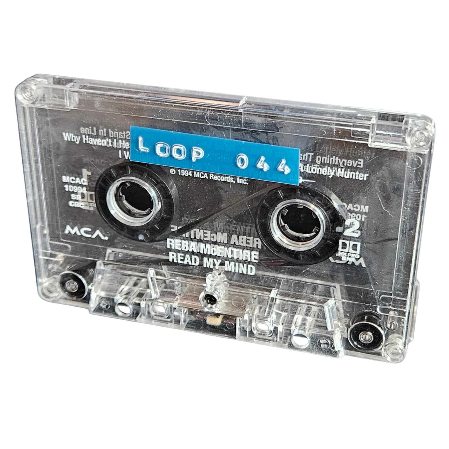 Clear cassette shell labeled Loop 044 on a blue strip, recycled from Reba McEntire's Read My Mind cassette